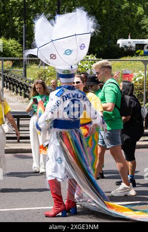 Une personne portant un costume coloré avec une coiffe élaborée, des bottes et une déclaration « Mind the Weather », représentant TFL à la London Pride 2024 Banque D'Images