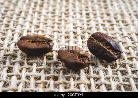 Gros plan de quelques grains de café couchés sur un fond de tissu de toile de jute. Contexte voor produits liés au café. Banque D'Images