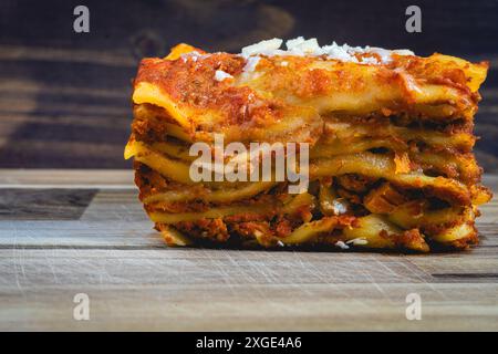 Vue rapprochée d'une lasagne faite maison, sur une table en bois, et un fond sombre. Banque D'Images