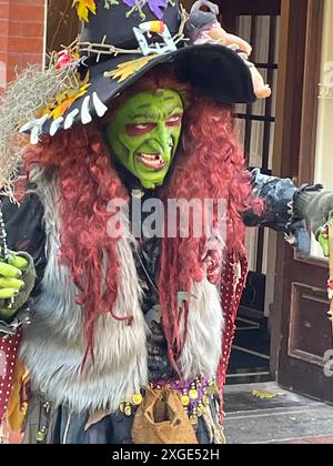 Une personne vêtue d'un costume de sorcière et d'un maquillage vert se produit pour un festival d'Halloween en utilisant la comédie et des insultes humoristiques Banque D'Images