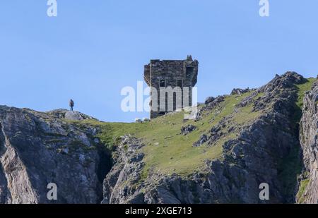 Homme debout, moutons qui paissent sur le promontoire côtier de l'Irlande à côté de la tour de signalisation napoléonienne Carrigan Head County Donegal Ireland. Banque D'Images