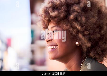 Vue latérale d'une jeune femme africaine joyeuse à l'extérieur profitant de la vue. Banque D'Images