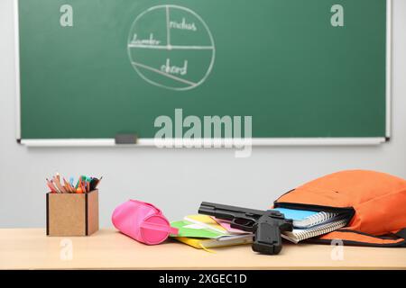 Papeterie scolaire, pistolet et sac à dos sur le bureau en classe Banque D'Images