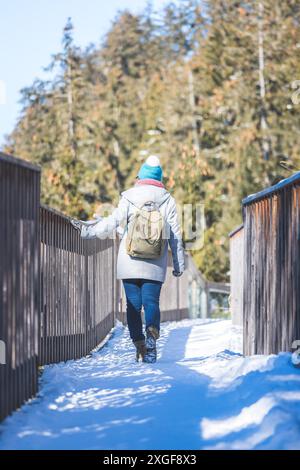 Une jeune femme marche sur un pont en bois enneigé Banque D'Images