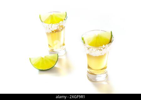 Photos de tequila avec des tranches de citron vert sur un fond blanc Banque D'Images