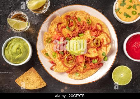 Nachos avec bœuf, coups de tequila, et divers trempettes, nourriture mexicaine et boissons au-dessus du plan à plat Banque D'Images