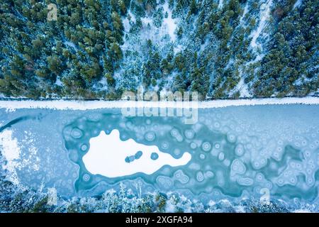 Vol au-dessus du lac gelé dans la forêt, Autriche. Photographie aérienne pendant la saison hivernale Banque D'Images