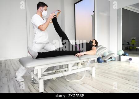 Physiothérapeute faisant des étirements musculaires de jambe chez une patiente. Traitement du nerf sciatique de la femme. Photo de haute qualité Banque D'Images