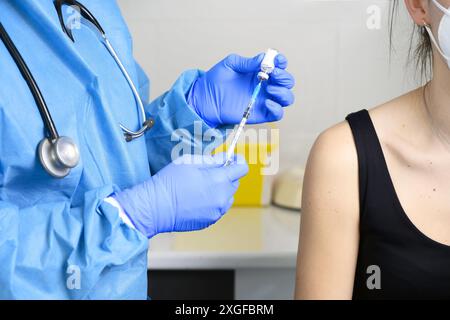 Gros plan de la jeune femme avec masque protecteur se faire vacciner, coronavirus concept. Photo de haute qualité Banque D'Images