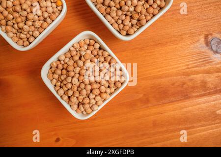Trois bols de pois chiches sur une table en bois brun clair, vue de dessus Banque D'Images