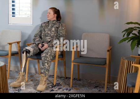 Assise dans la salle d'attente, femme en uniforme indéfini avec une jambe prothétique reposant, espace de copie Banque D'Images