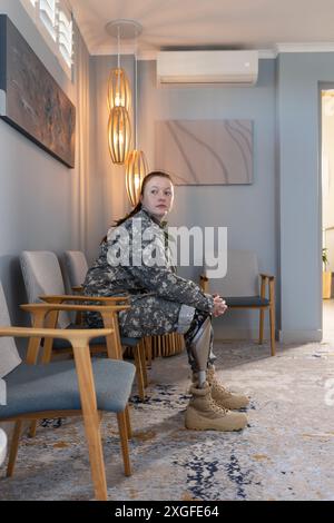 Assise dans la salle d'attente, femme en uniforme indéfini avec une jambe prothétique Banque D'Images