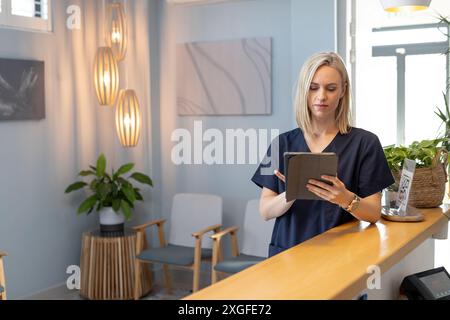En utilisant la tablette, professionnelle de santé féminine debout dans la clinique médicale moderne, espace de copie Banque D'Images