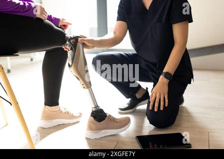 Ajustement de la jambe prothétique, professionnel de santé assistant le patient en salle de clinique Banque D'Images