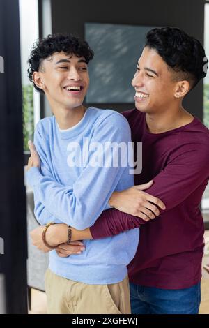 Couple gay masculin souriant embrassant et profitant du temps ensemble à la maison Banque D'Images