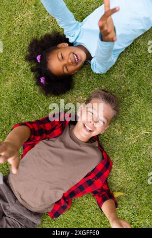 Portrait d'écoliers divers heureux couchés sur l'herbe à l'école Banque D'Images