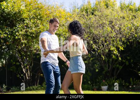 Danser ensemble, jeune couple profitant du temps à l'extérieur dans le jardin Banque D'Images