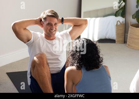 Exercice ensemble, couple faisant sit-ups sur tapis de yoga dans la chambre, souriant Banque D'Images