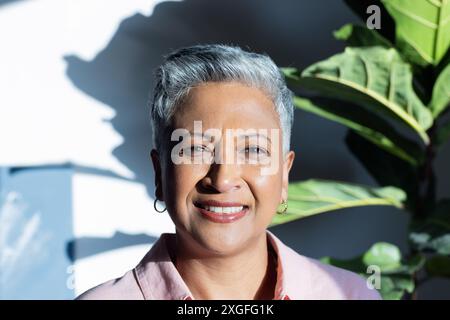 Femme âgée souriante avec les cheveux gris courts profitant d'une journée ensoleillée à l'intérieur Banque D'Images