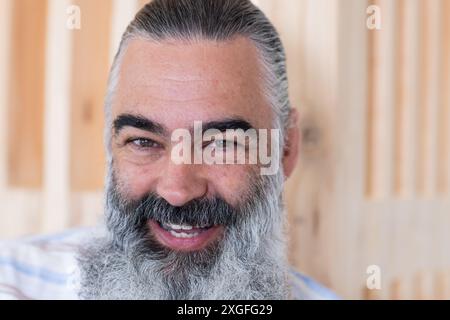 Homme âgé barbu souriant avec les cheveux gris posant pour le portrait, regardant la caméra Banque D'Images