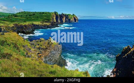 Côte accidentée avec des falaises abruptes et des vagues rugissantes brisant la mer bleue sous un ciel lumineux, Miradouro do Sertao, Capelas, île de Sao Miguel Banque D'Images