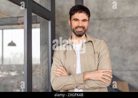 Homme debout avec les bras croisés par la porte vitrée dans le bureau Banque D'Images