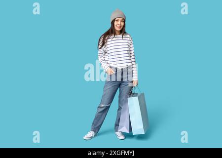 Jeune femme asiatique à la mode dans un Jean élégant avec des sacs à provisions sur fond bleu Banque D'Images