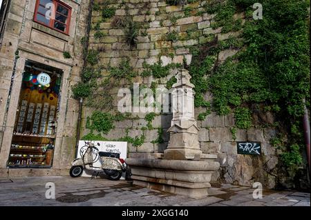 Coin pittoresque à Porto avec une vieille fontaine en pierre, une charmante boutique et un scooter vintage garé contre un mur couvert de vignes Banque D'Images