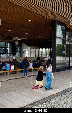 Une adolescente soutient sa mère alors qu'elle rampait à genoux autour de la chapelle des apparitions Banque D'Images