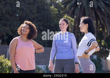 Exercice à l'extérieur, trois amies femmes en vêtements de sport profitant d'une journée ensoleillée ensemble Banque D'Images