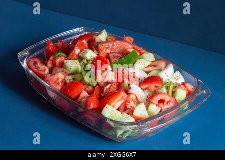 Plat en verre rempli d'une salade fraîche de tomates tranchées, concombres et poivrons verts, assaisonnés d'herbes, prêt à faire de la soupe gazpacho sur un beau Banque D'Images