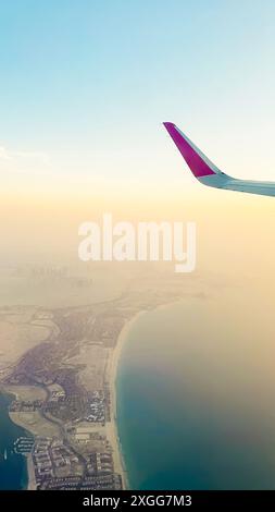 Point de vue des passagers fenêtre panorama de l'horizon d'Abu Dhabi et de la ville avec des rivières et un paysage déserté au coucher du soleil. Volez avec des compagnies aériennes à bas budget holi Banque D'Images