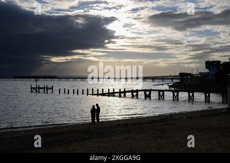 16 février 2024 : les amateurs de plage sur Southend-on-Sea Beach se silhouettent contre le soleil de fin d'après-midi. Banque D'Images