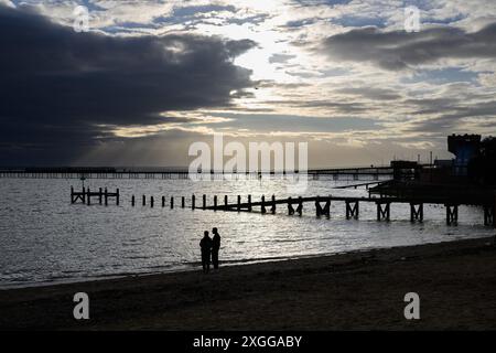 16 février 2024 : les amateurs de plage sur Southend-on-Sea Beach se silhouettent contre le soleil de fin d'après-midi. Banque D'Images