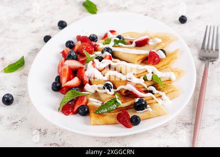 Crêpes aux baies et à la crème sure. Petit déjeuner sain. Petit déjeuner tardif. Crêpes Banque D'Images