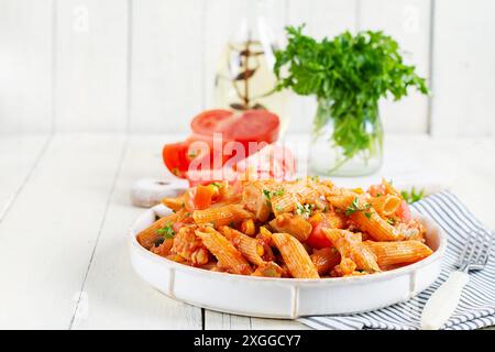 Pâtes italiennes classiques penne arrabbiata avec légumes sur table en bois blanc. Pâtes Penne à la sauce arrabbiata. Banque D'Images