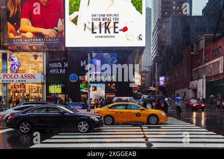Taxi jaune et circulation sur Times Square la nuit pendant une tempête de pluie intense Banque D'Images
