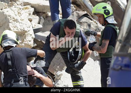 KIEV, UKRAINE - 8 JUILLET 2024 - les secouristes se lavent le visage lors d'une intervention dans une section d'un immeuble de cinq étages dans le district de Chevchenkivskyi ruiné par l'attaque de missiles russes, Kiev, capitale de l'Ukraine. Banque D'Images