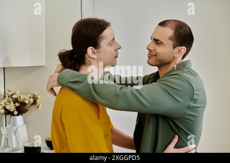 Un jeune couple gay s'embrasse dans un appartement moderne, mettant en valeur leur affection et leur connexion. Banque D'Images