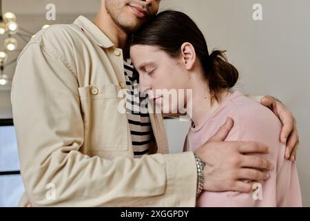 Un jeune couple gay s’embrasse dans un appartement moderne, mettant en valeur un moment tendre d’intimité et d’affection. Banque D'Images