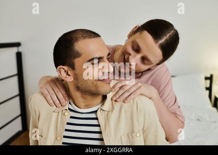 Un jeune couple gay partage un moment tendre dans leur appartement, l’un regardant l’autre avec amour et affection. Banque D'Images