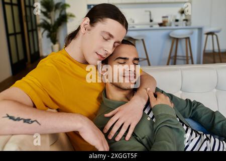 Un jeune couple gay se détend sur un canapé blanc dans leur appartement contemporain, mettant en valeur leur amour et leur connexion. Banque D'Images