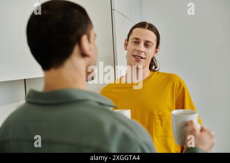 Un jeune couple gay aime une conversation informelle dans leur appartement moderne. Banque D'Images