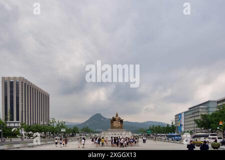 Statue emblématique du roi Sejong sur Seoul plaza, entourée de touristes, de bâtiments modernes et de montagnes. Banque D'Images