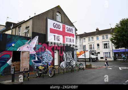 Brighton Royaume-Uni 9 juillet 2024 - Un panneau géant God Save the Team par l'artiste Corbyn Shaw juste à côté de Lewes Road à Brighton la veille de l'affrontement de l'Angleterre contre les pays-Bas dans leur match de demi-finale à l'Euro 2024 en Allemagne . Il fait partie de Buildhollywood qui se spécialise dans l'art créatif de la publicité de rue dans les villes britanniques : crédit Simon Dack / Alamy Live News Banque D'Images