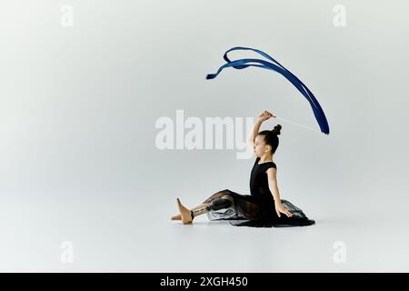 Une jeune fille avec une jambe prothétique pratique sa routine de gymnastique avec un ruban bleu. Banque D'Images