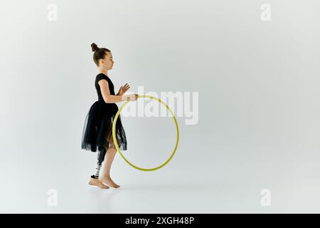 Une jeune fille avec une jambe prothétique pratique la gymnastique avec un hula hoop dans un studio blanc. Banque D'Images