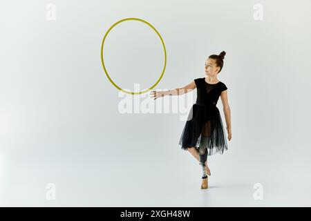 Une jeune fille avec une jambe prothétique pratique la gymnastique avec un cerceau dans un studio. Banque D'Images