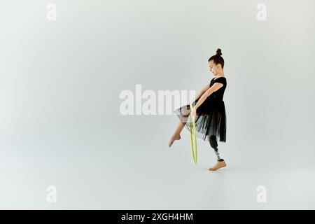 Une jeune fille avec une jambe prothétique pratique la gymnastique en utilisant un hula hoop. Banque D'Images