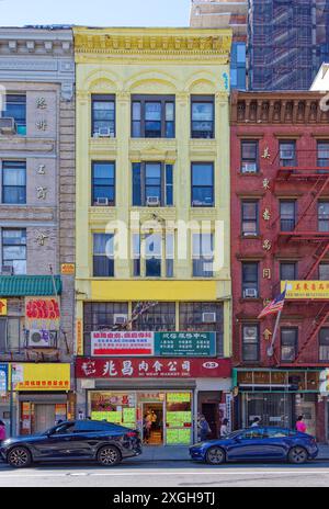 NYC Chinatown : 63 East Broadway est un loft de cinq étages en briques peintes en jaune avec des appartements au-dessus de deux étages commerciaux. Banque D'Images